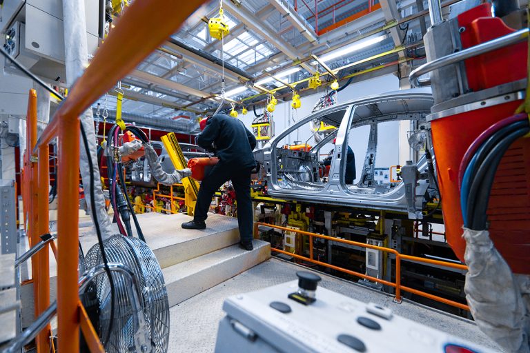 An industrial worker assembles cars in an industrial plant