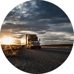 An 18-wheeler on the road at sunrise